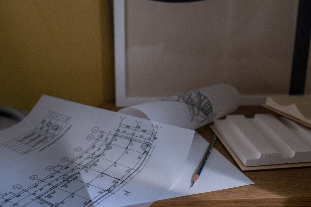 Plano estructural impreso sobre un escritorio, con lápiz y detalle de armado a la vista